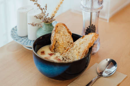 Potato soup topped with bacon and served with sourdough bread on the wooden tableの写真素材