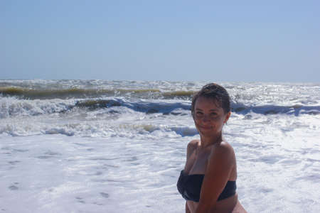 Beautiful girl enjoys the warmth on the sunny beachの写真素材