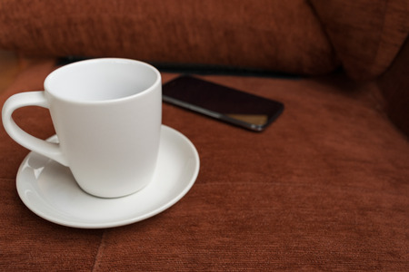 Cup,cup of coffee and blur smartphone on red carpet or red sofa backgroundの写真素材