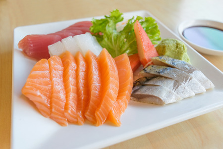 salmon and other fish raw with wasabi and sauce on table wood in restaurantの写真素材