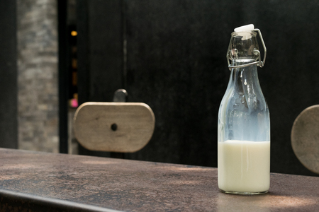 bottle of milk on table in front on black wall backgroundの写真素材
