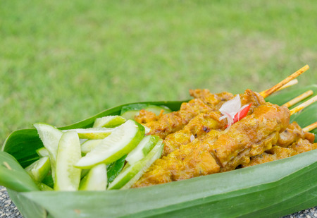 close up barbecue pork with cucumber in banana leaves with less spaceの写真素材