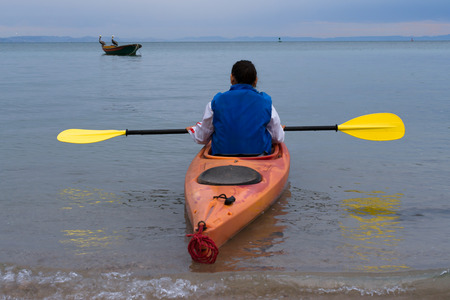 The girl walks away from the beach in her kayaks.の写真素材