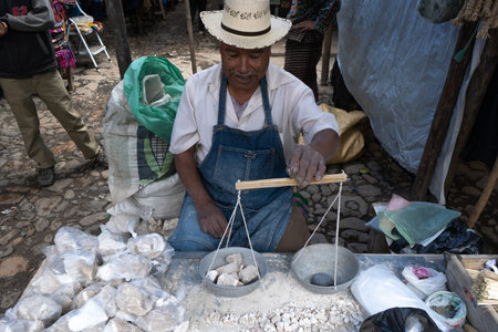 Chichicastenango, Guatemala - October 10, 2019: The gentleman is weighing and selling stones at the market in Chichicastenango.のeditorial素材