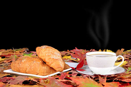 Coffee cup and breakfast and autumn maple leaves are on a wooden tableの写真素材