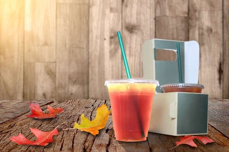 Tasty espresso and take-out coffee, cups in holder, coffee cups in holder and paper bag on the old wood floor, and autumn maple leaves are on a wooden tableの写真素材