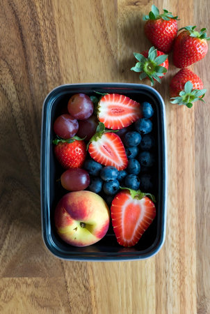 Strawberries and blueberries in a bowl on a wooden backgroundの素材