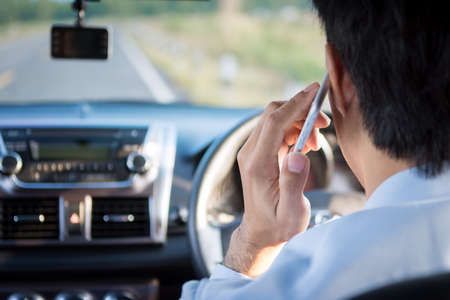 Asia Man talking on a mobile phone while driving car.