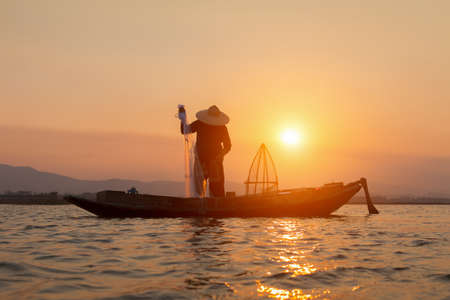 Silhouettes of the traditional stilt fishermen at sunset.の写真素材