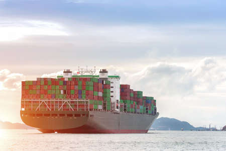 Container Cargo freight ship with working crane bridge in shipyard at dusk for Logistic Import...