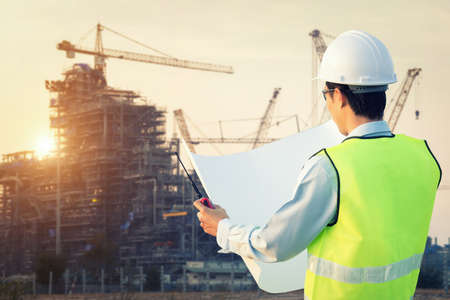 Engineer in uniform and helmet on of background the Construction Site oil rig 