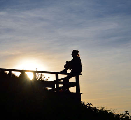 silhouette of lady sitting on the edgeの写真素材