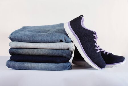 Sneakers and a stack of jeans on a white backgroundの写真素材