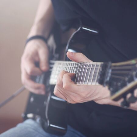 Repetition of rock music band. Cropped image of hands electric guitar playerの写真素材