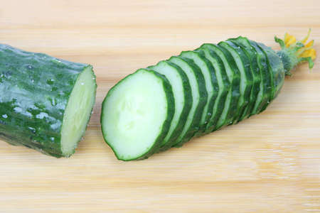 a cucumber cut in slices isolated on cutting boardの写真素材