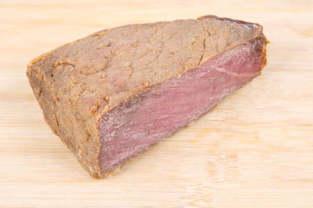 a piece of cooked beef on the bamboo chopping boardの写真素材