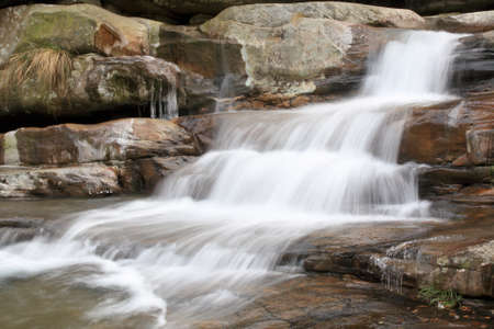 flowing brook on the rocks in winter, long exposure の写真素材