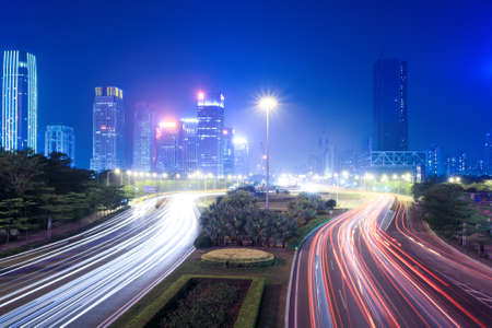 the light trails on the street with modern city background at nightの写真素材