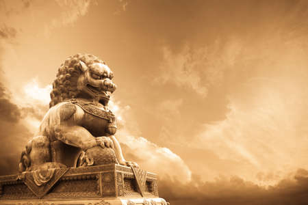 a majestic lion statue in the forbidden city with changing skyの写真素材