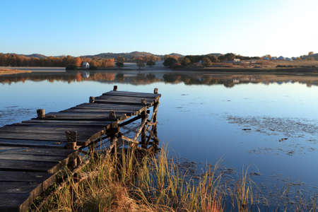 wooden pier in tranquil lake at morningの写真素材