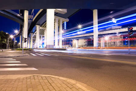 city highway at night, light trails under grade separation bridge