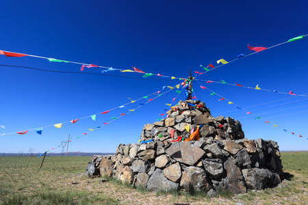 praying stone and prayer flags on steppe in inner mongoliaの写真素材