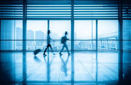 commuters motion blurred with modern corridor in high speed rail station