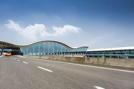 airport terminal against a blue sky with the dynamic background of highwayのeditorial素材