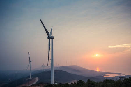 the rising sun shine in wind farm by the lakeの写真素材