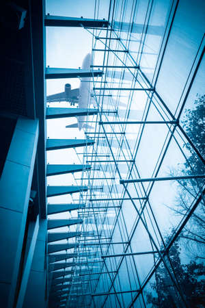 glass curtain wall closeup, airplane above the modern buildingのeditorial素材