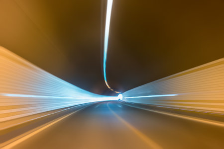 curve tunnel inside and road exit to light with car driving motion blurの写真素材