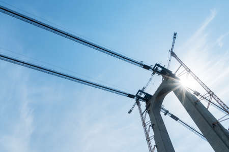 bridge tower in construction with crane against a sunlight skyの写真素材