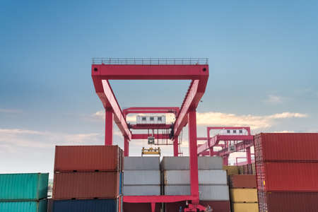 shipping containers with gantry crane closeup against a dusk skyのeditorial素材