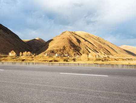 empty asphalt road with the autumn sun shines in the tibetan area, highway backgroundの写真素材
