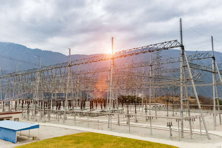 high voltage power transformer substation in valley against a cloudy skyの写真素材