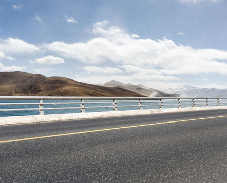 empty asphalt road with holy lake in tibetの写真素材
