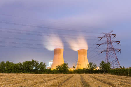 power plant on farmland at night, long time exposure of cooling towers steamの写真素材