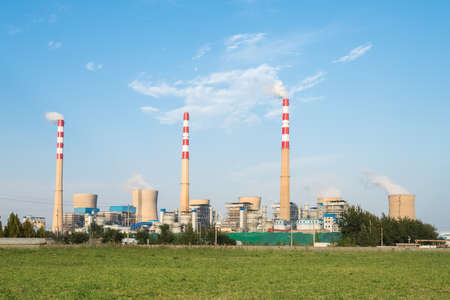 large power plant with green grass against a blue skyのeditorial素材
