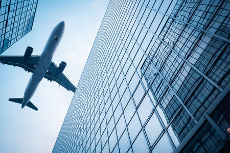 upward view of modern glass skyscraper and airplane  のeditorial素材