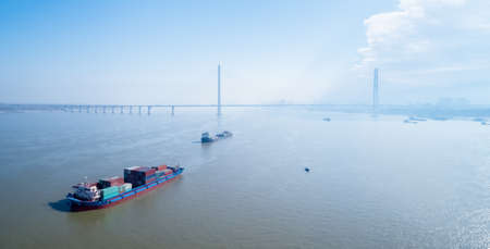 container ship on yangtze river with jiujiang cable-stayed bridge background, Chinaの写真素材