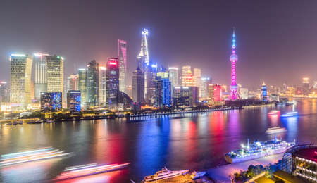shanghai skyline in evening, light trails of pleasure boat on huangpu river