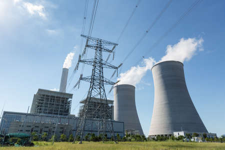 thermal power plant and high voltage transmission pylon against a blue sky