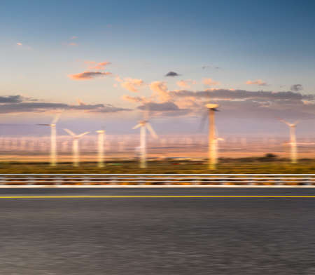 Dusk wind farm and highway motion blurred background