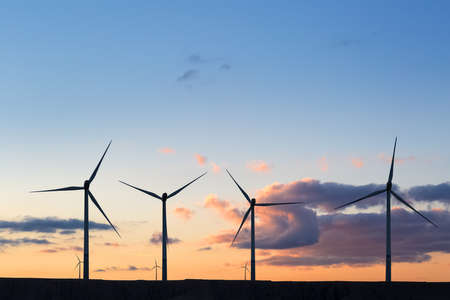 silhouette of wind turbine generator against af sunset sky