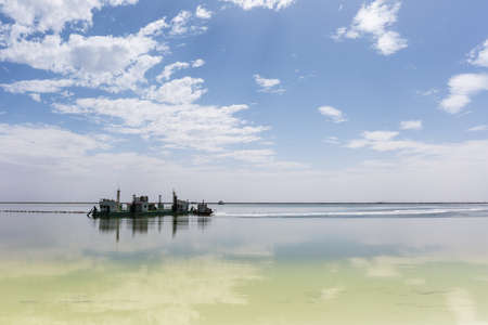 salt mining ship and blue sky reflection in qarhan salt lake, golmud city, qinghai province, China