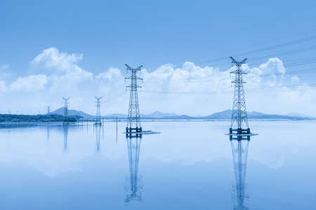 power transmission tower and reflection on the calm surface of the lake