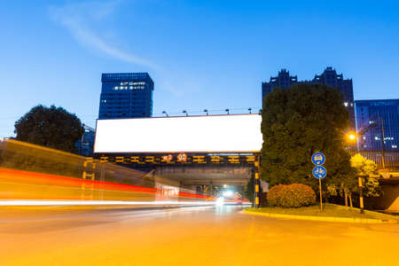blank light box billboard on railway bridge in nightfall with light trails on city road, clipping pathの写真素材