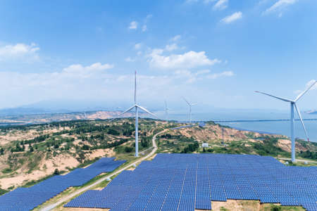 new energy by lakeside, wind farm and solar power with sunny skyの写真素材