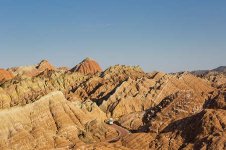 beautiful hilly landscape and bus through winding road in zhangye danxia national geological park, gansu province, China.の写真素材