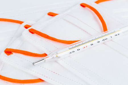 thermometer closeup on disposable medical mask, personal health monitoring and protection backgroundの写真素材